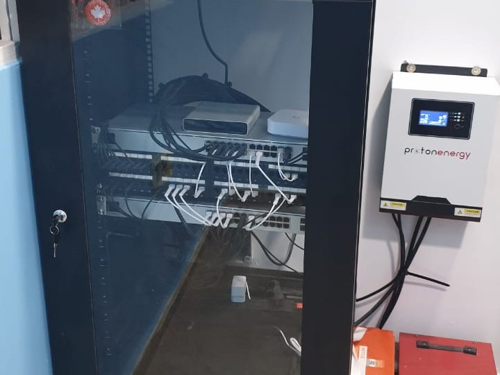 An installed comms rack with patch panel, switching and structured cabling, with battery-backed power alongside