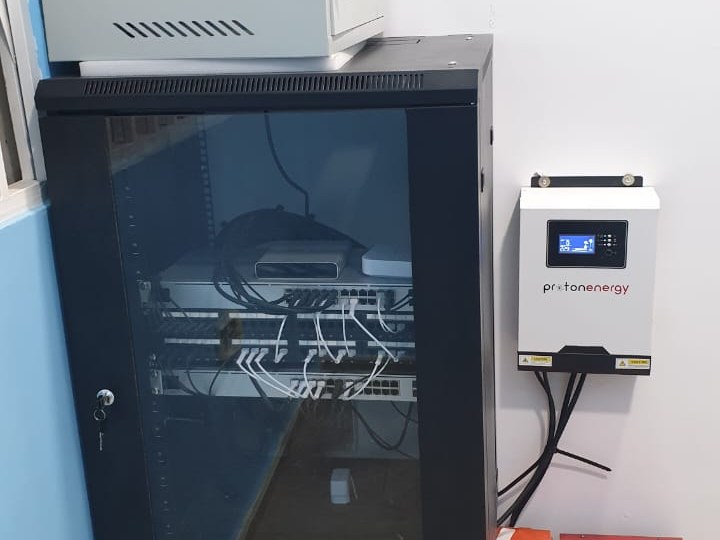 A floor-standing comms rack and wall cabinet with an inverter and battery backup installed alongside